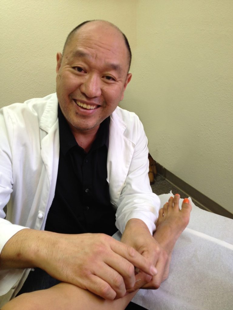 Dr. Robert Chu demonstrating acupuncture treatment during a clinical session.